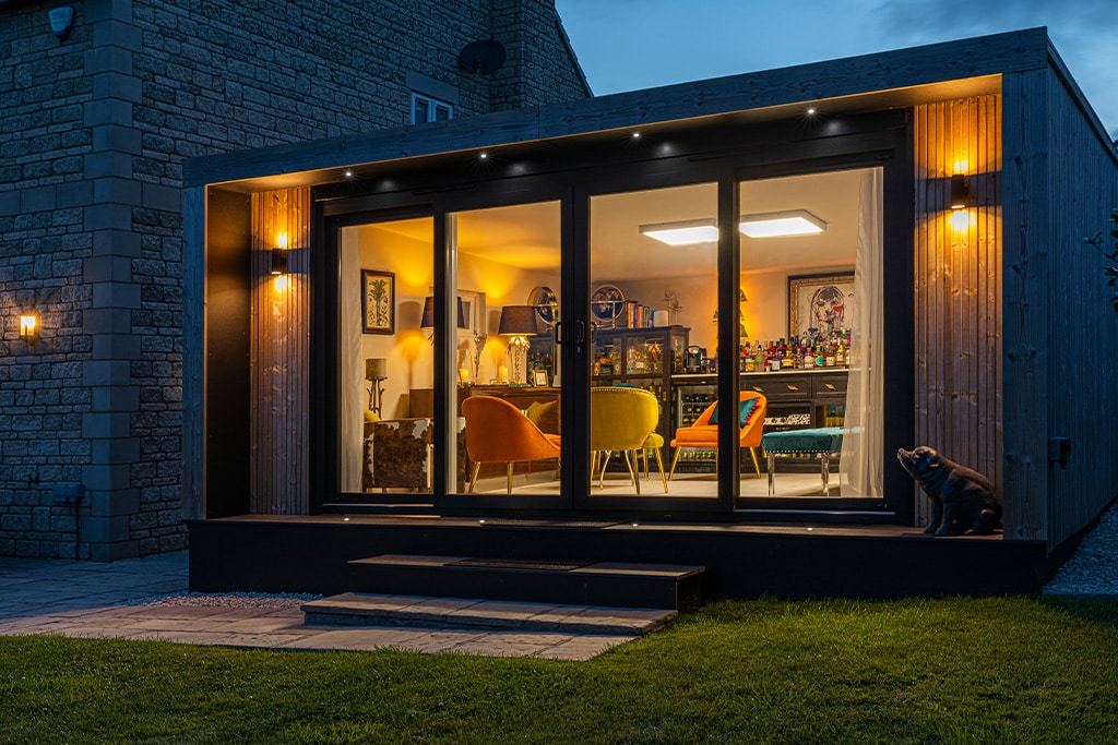Premium garden room with a glass facade at dusk
